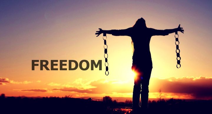 Woman standing with outstretched arms with sun in the background. Chain links hang from each arm. "Freedom" printed next to her.